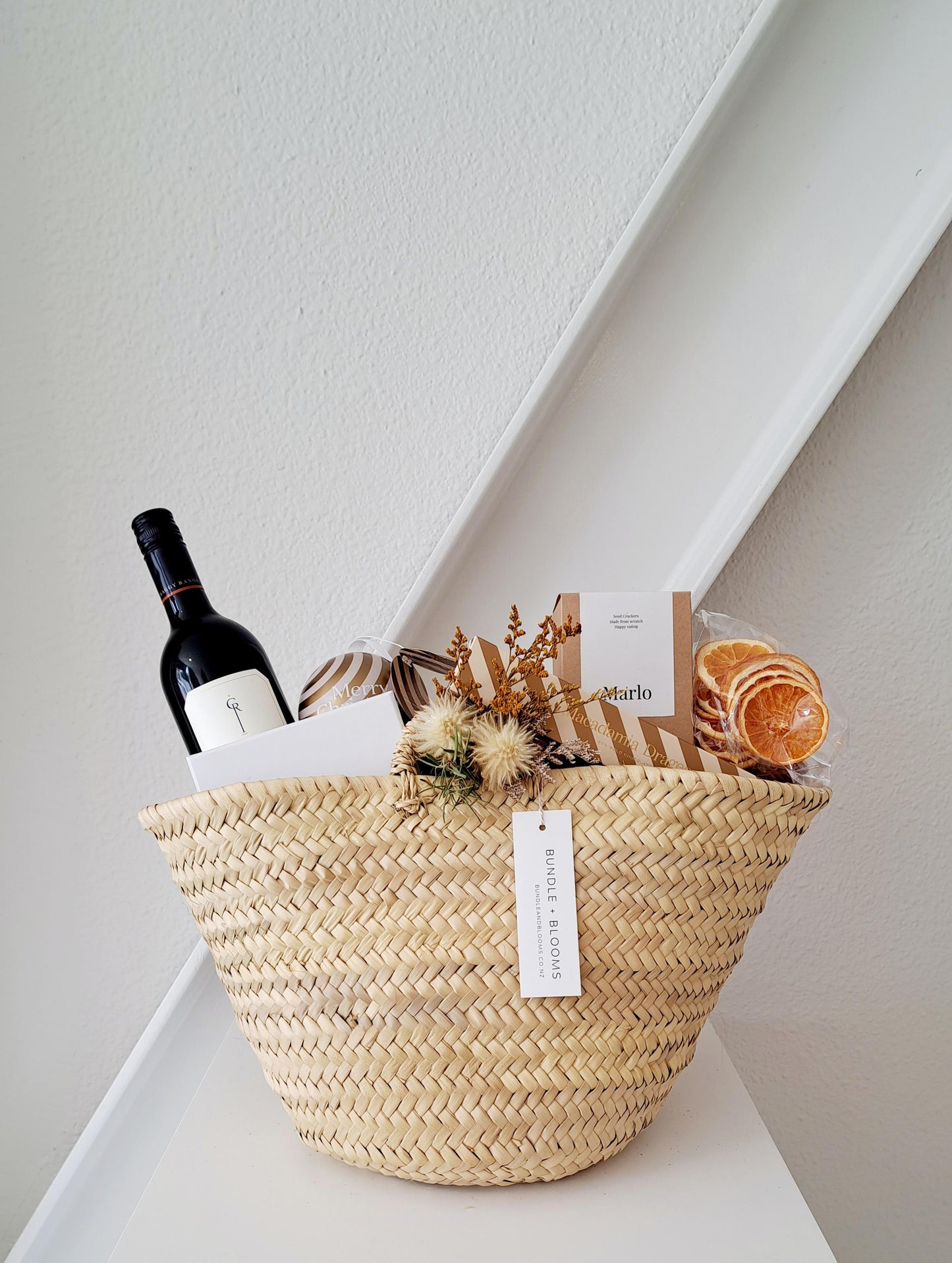 Golden Christmas Market Basket with wine, artisan chocolates, and festive gourmet treats by Bundle + Blooms.