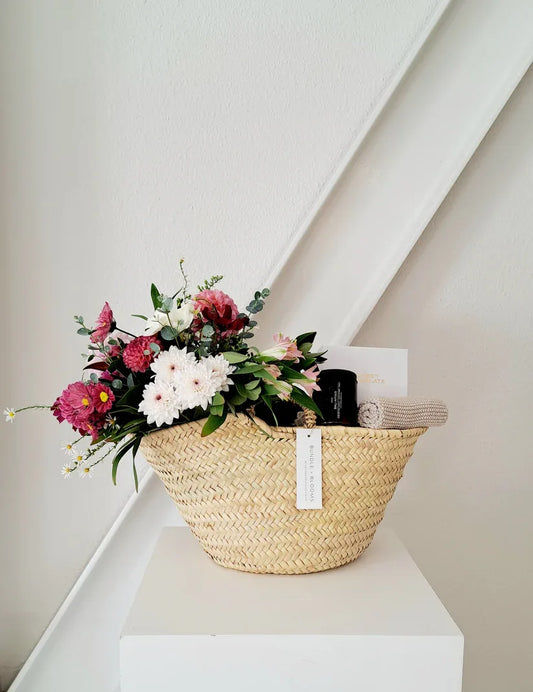 Mother’s Day gift basket with a candle, chocolates, and seasonal flowers.