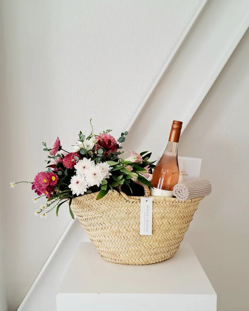 Luxury gift basket with wine, chocolates, and seasonal flowers.