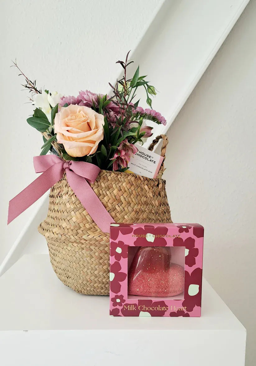 Woven basket with handles, chocolates, and seasonal floral arrangements.